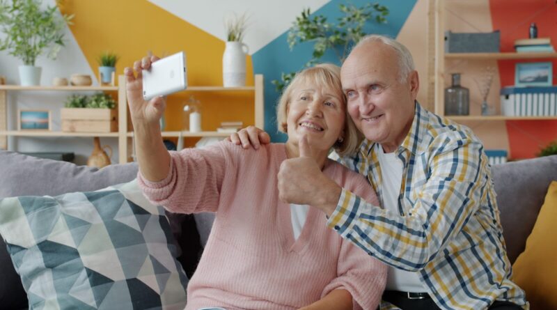 Elderly couple taking a selfie on the couch.